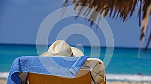 Vacationer in a white hat on a sun lounger on a cuban beach of white sand against the background of the sea