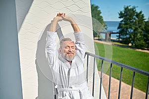 Vacationer in a white terry bathrobe basking in the sunshine