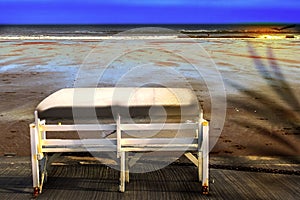 Vacations background. Tropical scenery with empty bench on the beach.