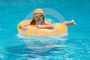 Vacations and summer recreation with children. Child boy 7, 8, 9 years old swim on floating ring in swimming pool. Kids