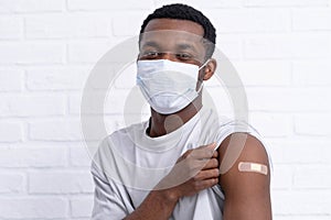 vaccinated African American man showing arm with medical plaster patch Plaster On Shoulder, black female after getting