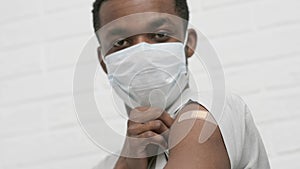 vaccinated African American man showing arm with medical plaster patch Plaster On Shoulder, black male after getting