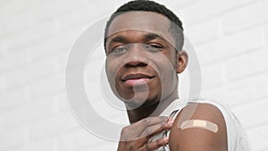 vaccinated African American man showing arm with medical plaster patch Plaster On Shoulder, black male after getting