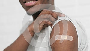 vaccinated African American man showing arm with medical plaster patch Plaster On Shoulder, black male after getting