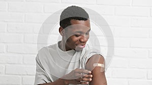 vaccinated African American man showing arm with medical plaster patch Plaster On Shoulder, black male after getting