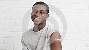 vaccinated African American man showing arm with medical plaster patch Plaster On Shoulder, black male after getting