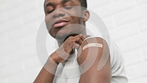 vaccinated African American man showing arm with medical plaster patch Plaster On Shoulder, black male after getting