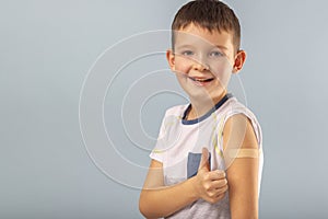 Vaccinated boy gesturing with thumbs up, showing hand with plaster cast after injection of coronavirus vaccine. Start of