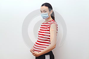Vaccinated woman showing arm with bandage after covid-19 vaccine injection. Pregnant vaccination