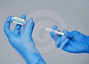 Vaccination against covid-19. A doctor in blue gloves holds a syringe and an ampule with a vaccine.