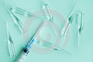 Medical syringe and glass ampules with vaccine or medicine on blue background, top view, flat lay