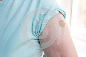 Vaccination elderly woman in doctor office with adhesive covid-19 vaccine plaster.