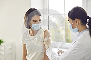 Young woman in a protective face mask getting an antiviral vaccine at the clinic