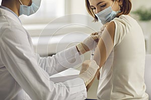 Young woman in face mask getting Covid-19 or flu antiviral vaccine at doctor`s office