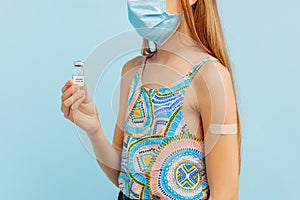 Vaccination of a little girl, a child with an adhesive plaster on his hand holds a bottle with a vaccine against coronavirus covid