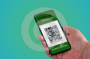 Vaccination passport for COVID-19 displayed on smartphone held in male`s hand with copy space isolated on green background. Vaccin