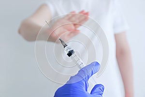 Vaccination refusal concept. Syringe with vaccine in hand hand refusal gesture
