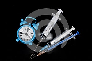 Vaccination time. Vaccine in vial with syringe on clock background. Prevention immunization illness