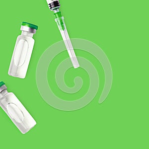 Vaccine Bottles And Needle Syringe On Green Background