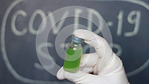 Vaccine. Close up of microbiologist or medical worker hand with surgical gloves holding an antidote medicine for the new