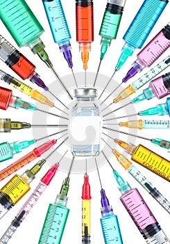 Vaccine cure concept. Drug vial with blank label surrounded by colorful syringes with needles pointed towards vaccine