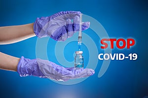 Vaccine.The hand of a doctor in medical gloves holds a bottle and fills a syringe with medicine. Blue background.Stop COVID-19.