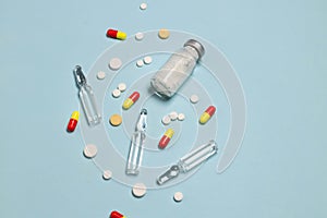Vaccine and syringe, assorted pharmaceutical medicine pills, tablets and capsules on blue background. Healthcare and