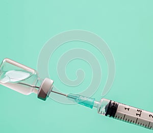 Vaccine vial dose and syringe against green background