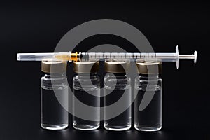 Vaccines, botulinum toxin and insulin ampules concept theme with glass vials with clear liquid next to a syringe and a hypodermic photo