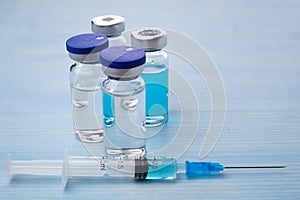 Vaccines and syringes on blue wooden table