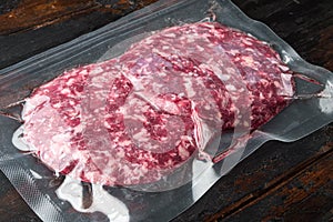 Vacuum beef cutlet sealed airtight pack, on old dark  wooden table background
