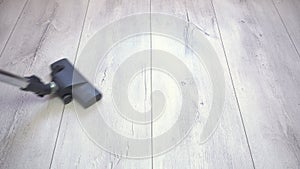 Vacuum cleaner brush removes dust from gray laminated flooring. Apartment cleaning, vacuuming gray parquet and laminate