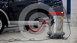 Vacuum cleaner and car. General plan of the sink. A worker vacuums the interior of a car at a car wash.