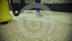 Vacuum cleaner cleans the carpet. A man from a cleaning company works, vacuuming the carpet