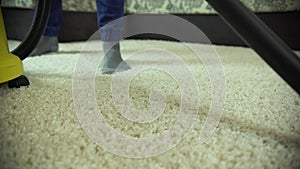 Vacuum cleaner cleans the carpet. A man from a cleaning company works, vacuuming the carpet