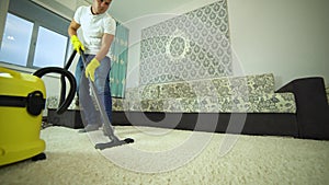 Vacuum cleaner cleans the carpet. A man from a cleaning company works, vacuuming the carpet