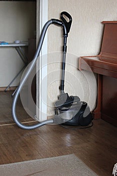 Vacuum cleaner located in the room near the piano