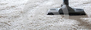 Vacuum cleaner in use on a white fluffy carpet. Rug cleaning. Vacuuming. Concept of household chores, home hygiene