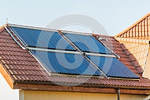 Vacuum collectors- solar water heating system on red roof of the house