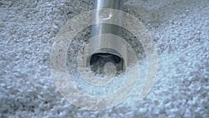 Vacuum loader hose sucking white virgin plastic granules from tank in factory workshop