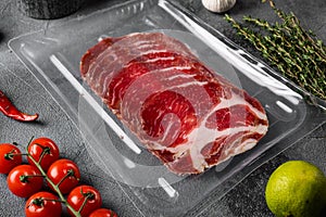 Vacuum packed cured coppa ham , on gray stone table background