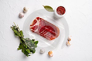 Vacuum packed cured coppa ham , on white stone table background, top view flat lay, with copy space for text
