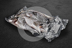 Vacuum-packed fish, on dark stone background, dorada. Semifinished