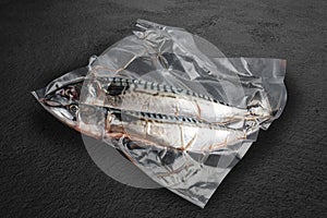 Vacuum-packed fish, on dark stone background, mackerel. Semifinished