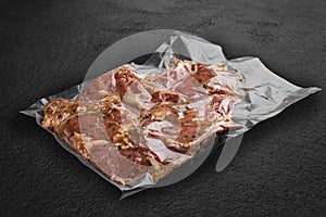 Vacuum-packed meat, on dark stone background, pork steak. Semifinished photo