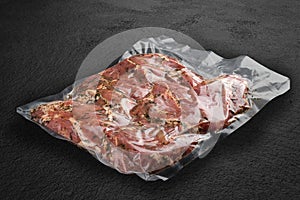 Vacuum-packed meat, on dark stone background, veal steak. Semifinished