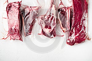 Vacuum packed organic raw beef classic cuts, tomahawk, t bone, club steak, rib eye and tenderloin cuts, on white stone  background