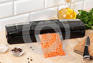 Vacuum packing machine. For long-term storage of food. Packs chopped carrots. Top view light background