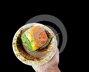 Vada pau bread and green sauce on a plate in dark background on hand