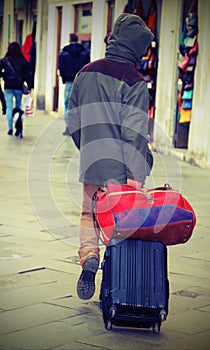 Vagabond with suitcase luggage trolley in Venice with vintage effect